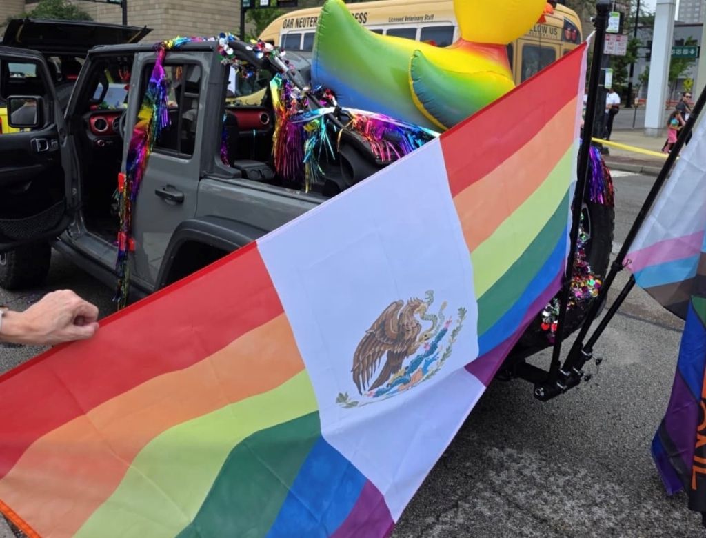 Colorful Pride parade float with Mexican flag and rainbow decorations on a vehicle.