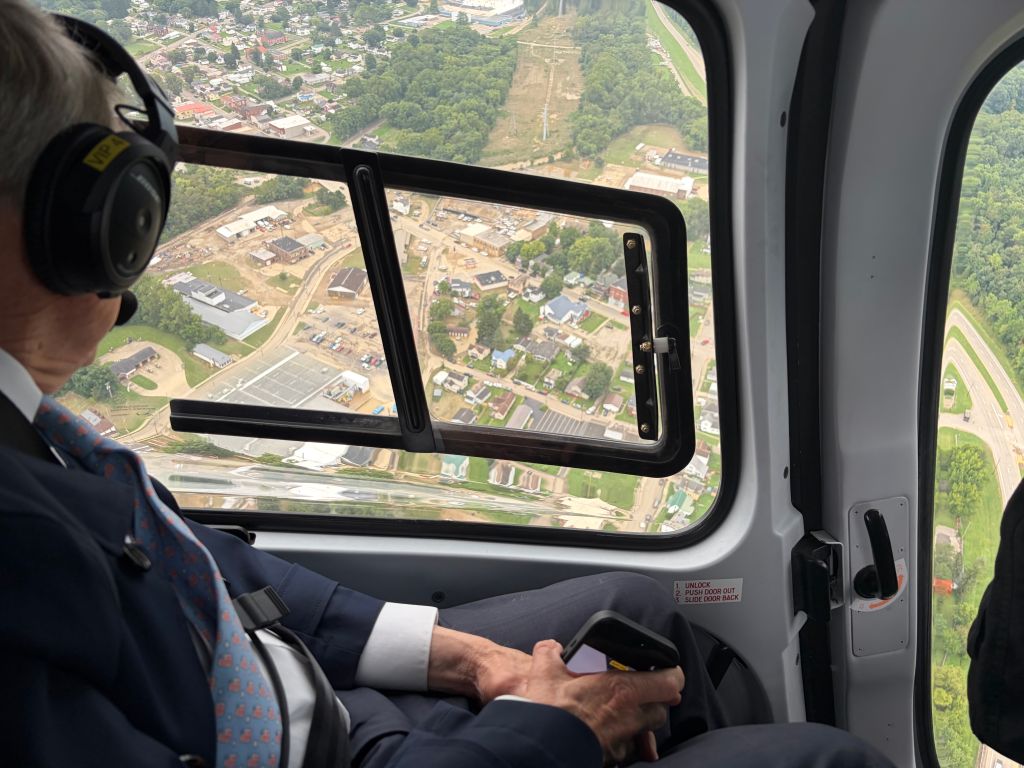 View from the window of an aircraft showing a town and surrounding countryside below.